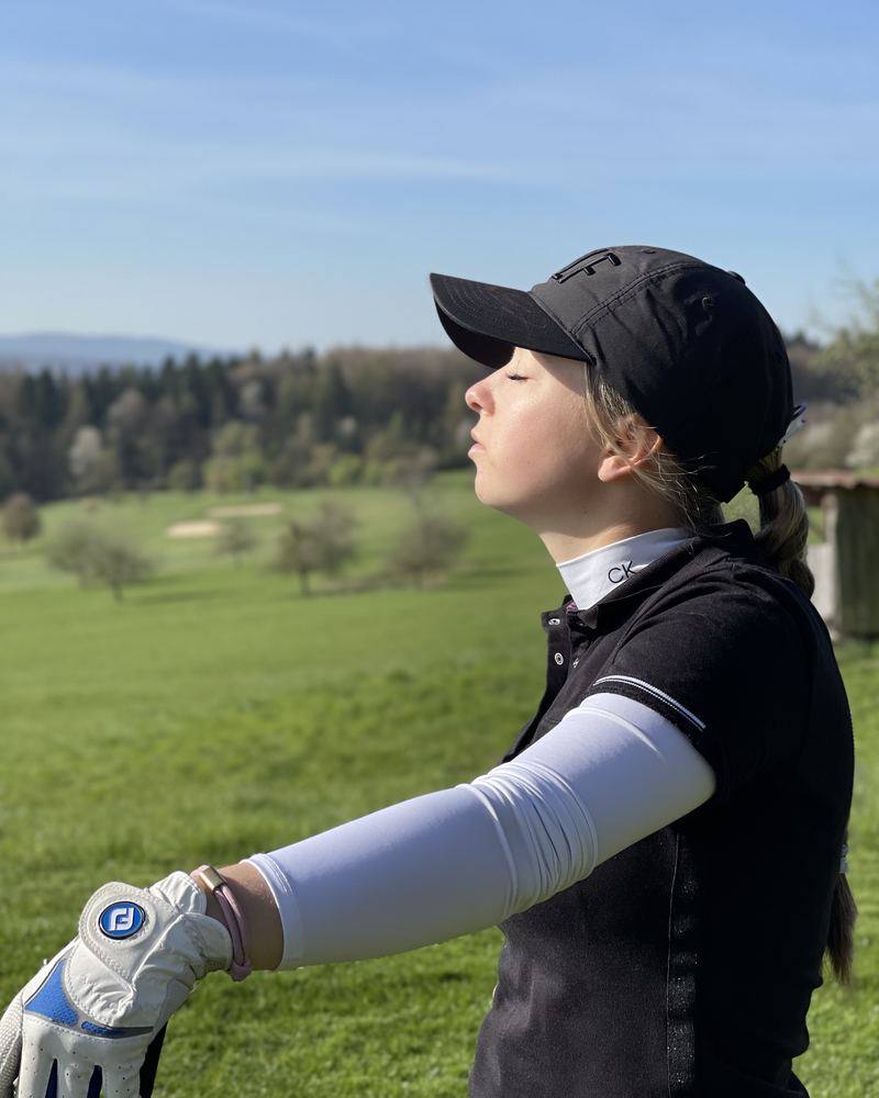 Marie Martin mit geschlossenen Augen auf dem Golfplatz — mentale Vorbereitung vor dem Schlag